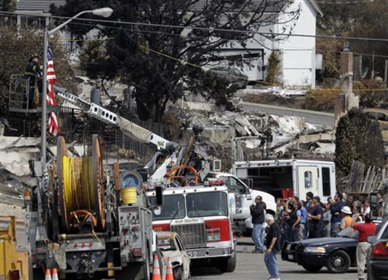 Residents, bottom right, witness the raising of a U.S. flag at the site of a gas pipeline explosion in San Bruno, Calif., on Monday.